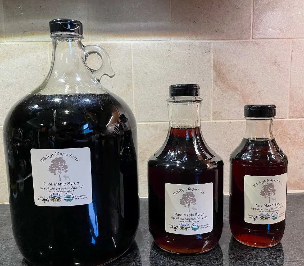 Three sizes of glass bottles containing pure, organic maple syrup from Elk Ridge Maple Farm in Wisconsin.